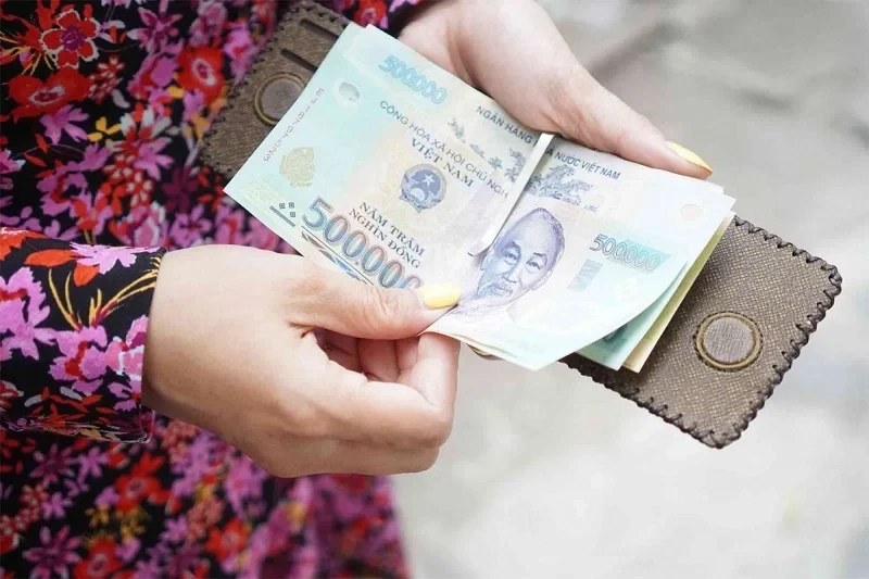 A hand holding several 500,000 Vietnamese dong notes