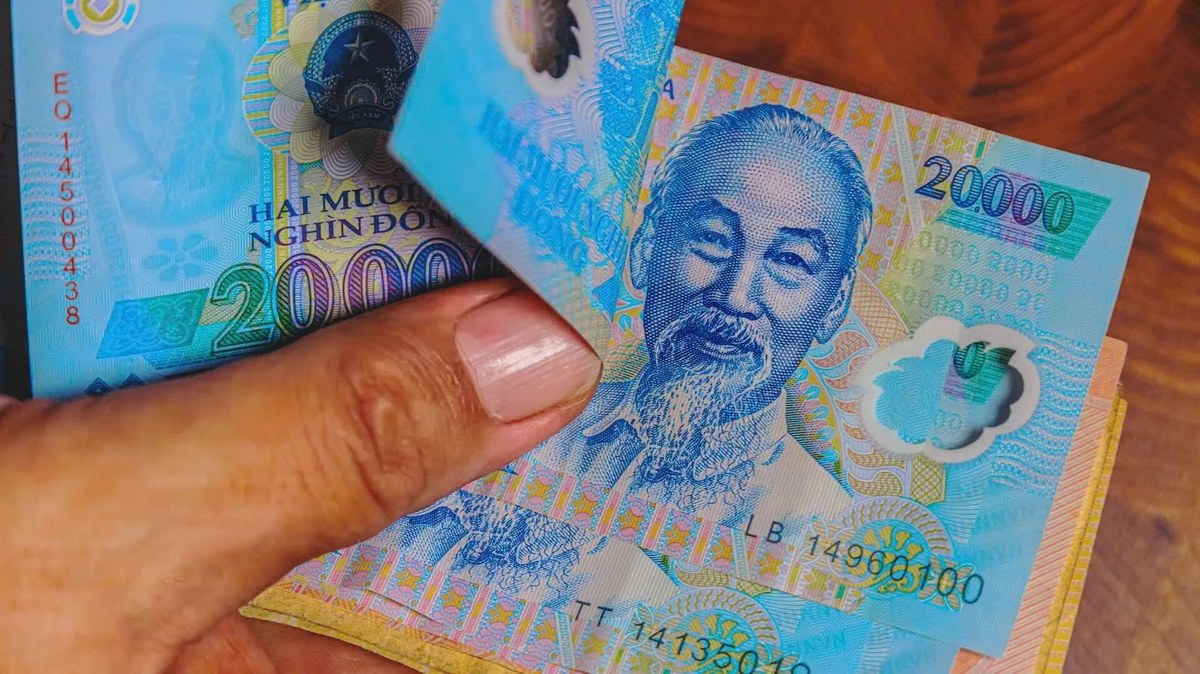 A hand holding blue 20,000 Vietnamese dong notes, which look similar to the 500,000 note